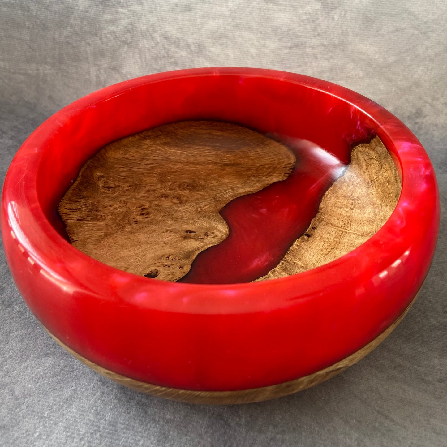 Red bowl with natural wood interior on a gray background