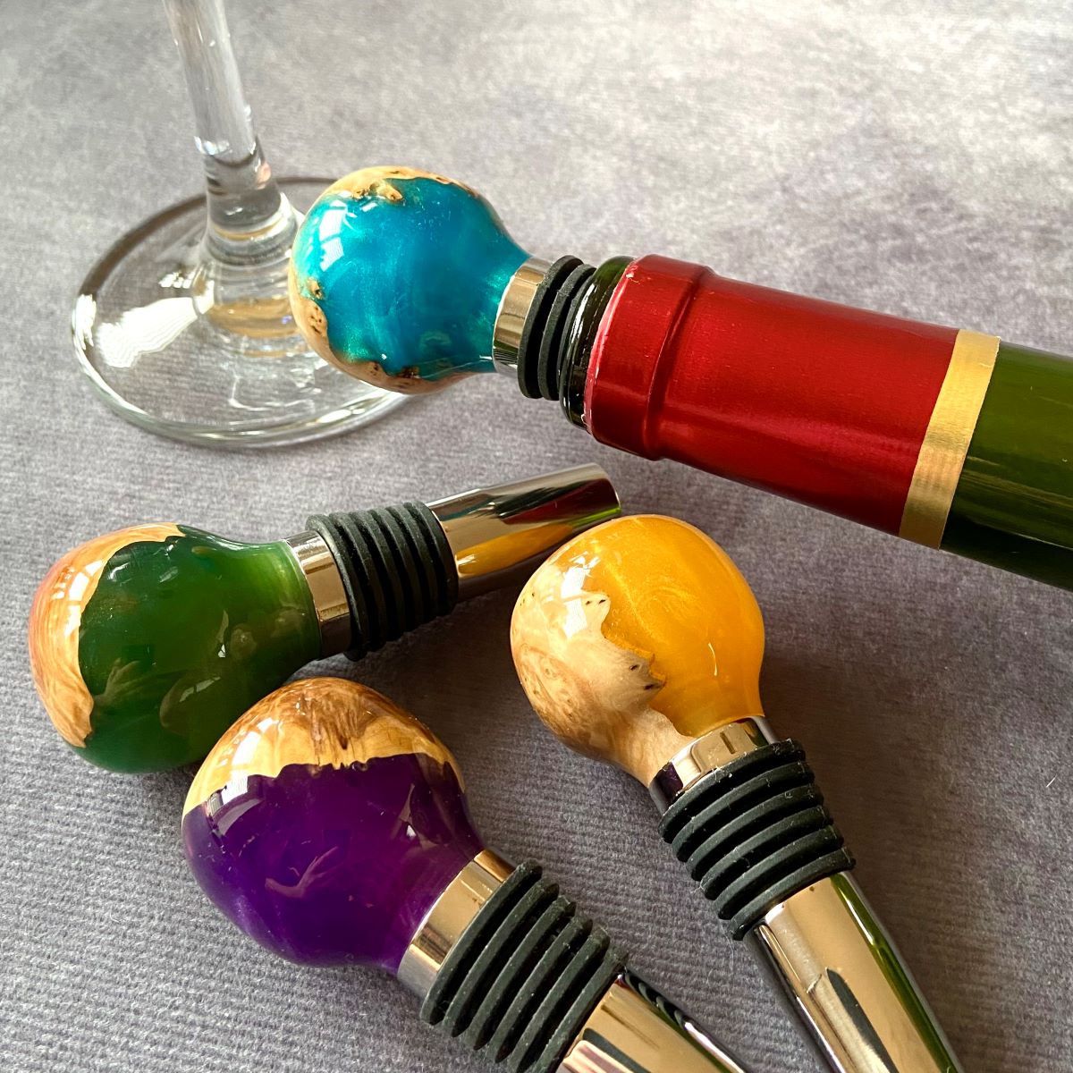 Group view of mallee burr and resin wine stoppers with wine glass
