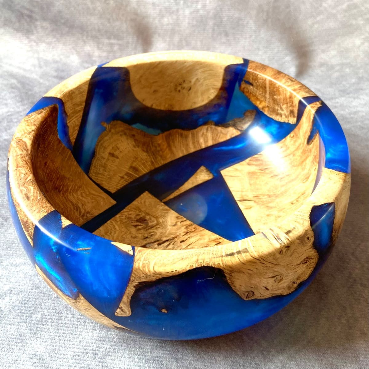Top down view inside handmade bowl showing floating wood pieces in blue resin