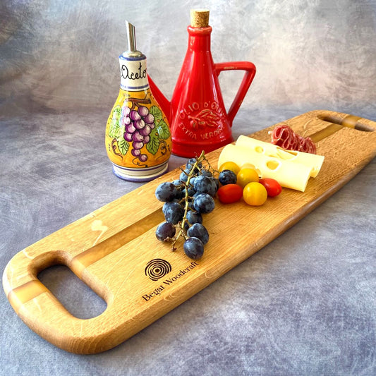 Wooden charcuterie board with oil bottles shown with cheese and grapes