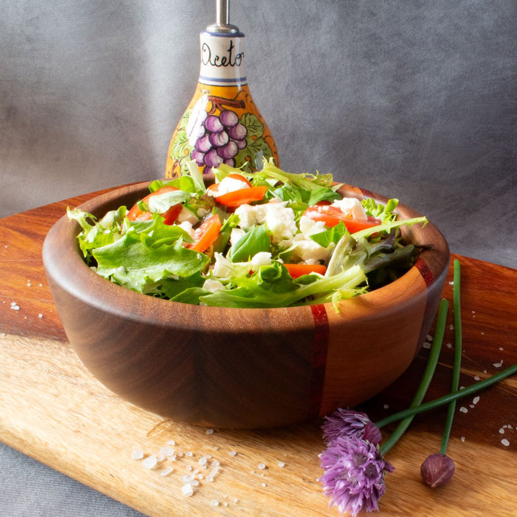 View of small wooden salad bowl in walnut, cherry and padauk filled with salad