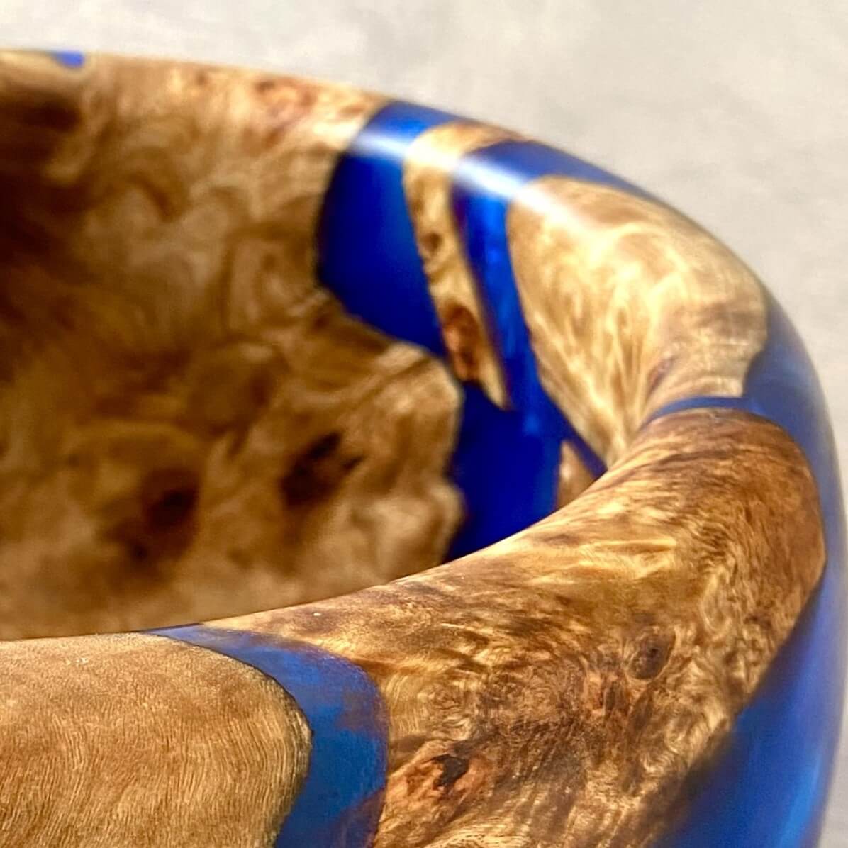 Close up detail of Mappa Burr wood grain and vivid Cobalt Blue resin fusion on handmade artisan bowl