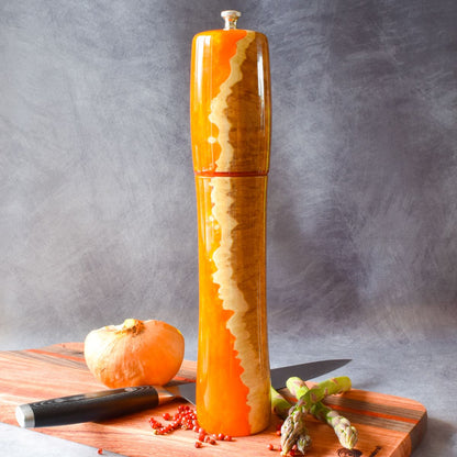 Mallee burr & orange resin pepper mill on charcuterie board front view