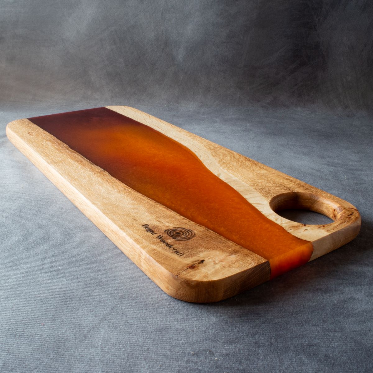 Medium charcuterie board in english oak with orange and red resin viewed from the handle end