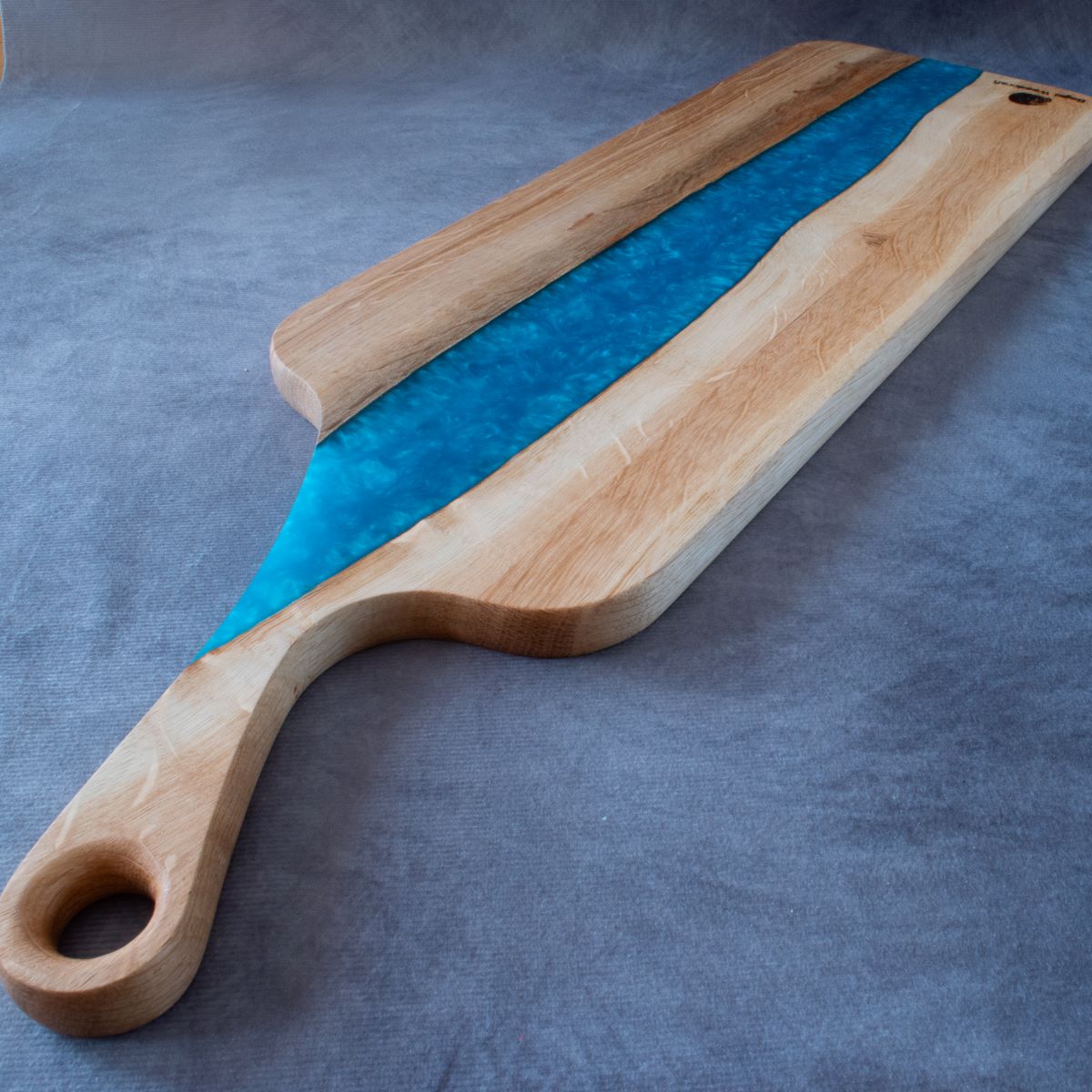 Charcuterie board in English oak and turquoise resin viewed from handle end