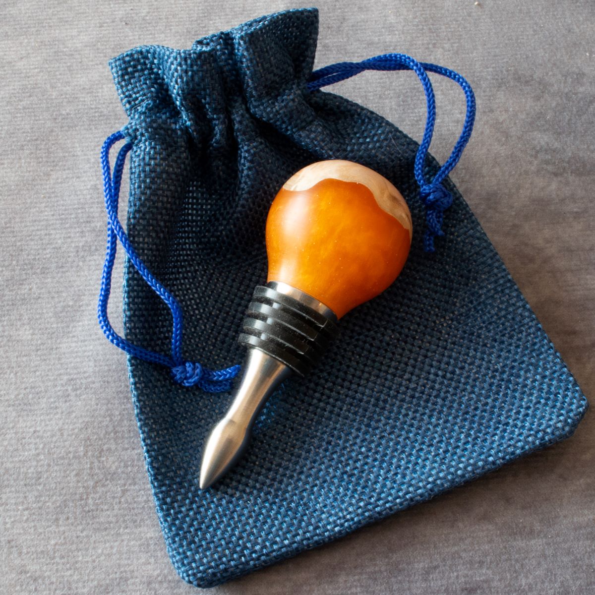 Wine stopper in mallee burr & orange resin displayed with cloth bag