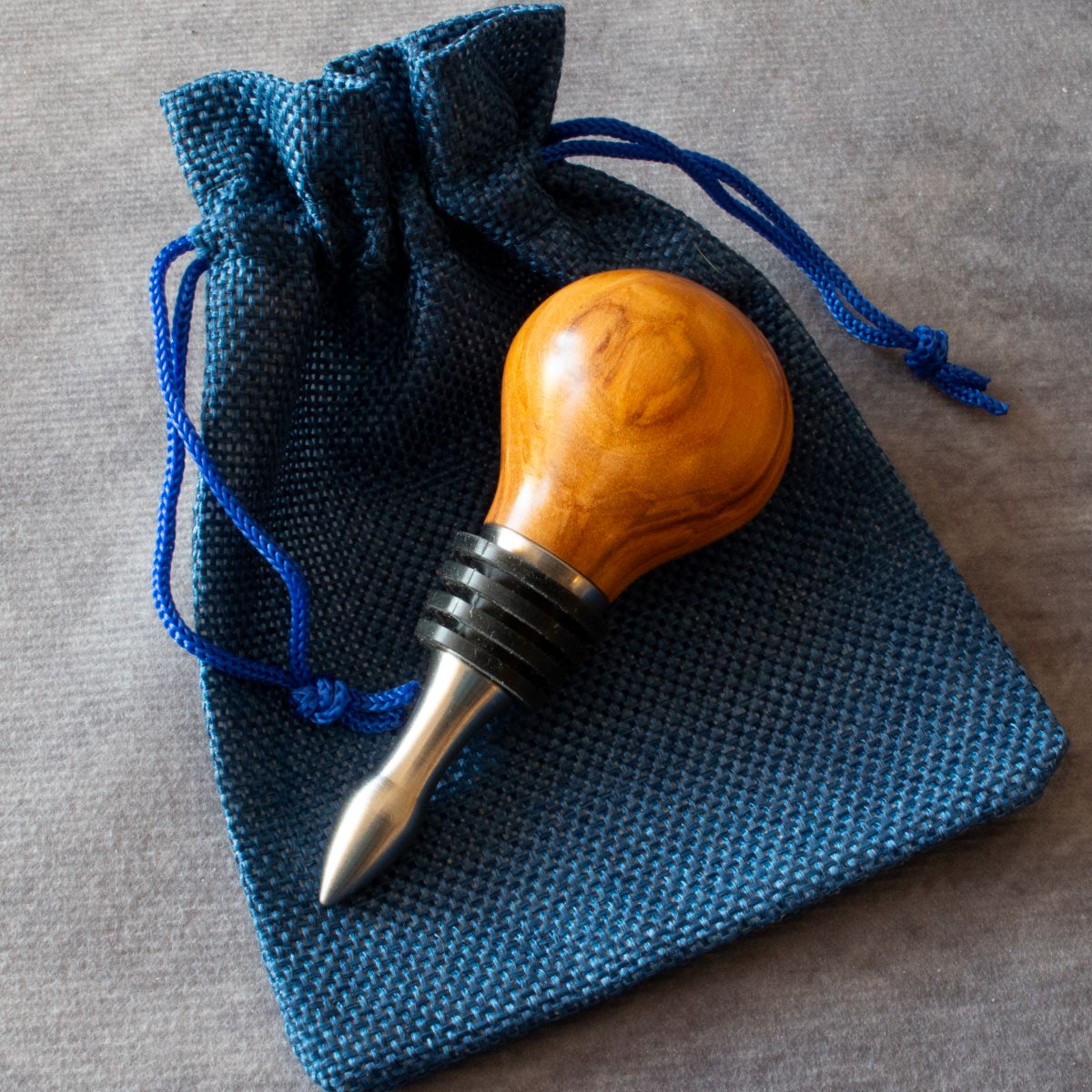 Wine stopper in olive wood displayed with cloth bag