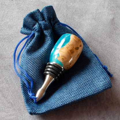 Wine stopper in mallee burr & turquoise resin pictured on blue bag