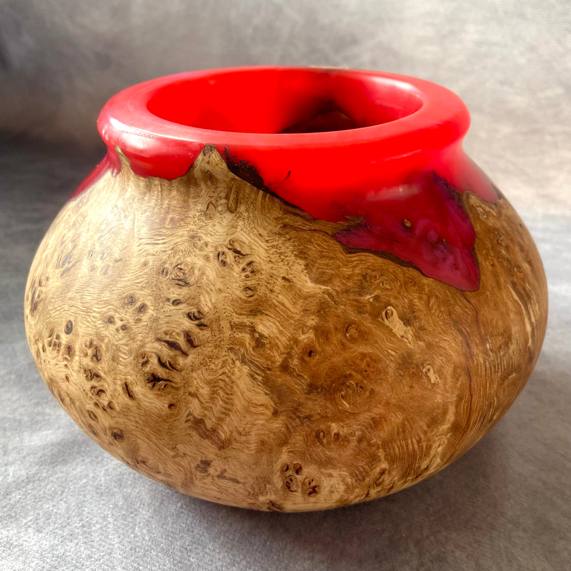 Vessel with red top and wooden base on a gray background