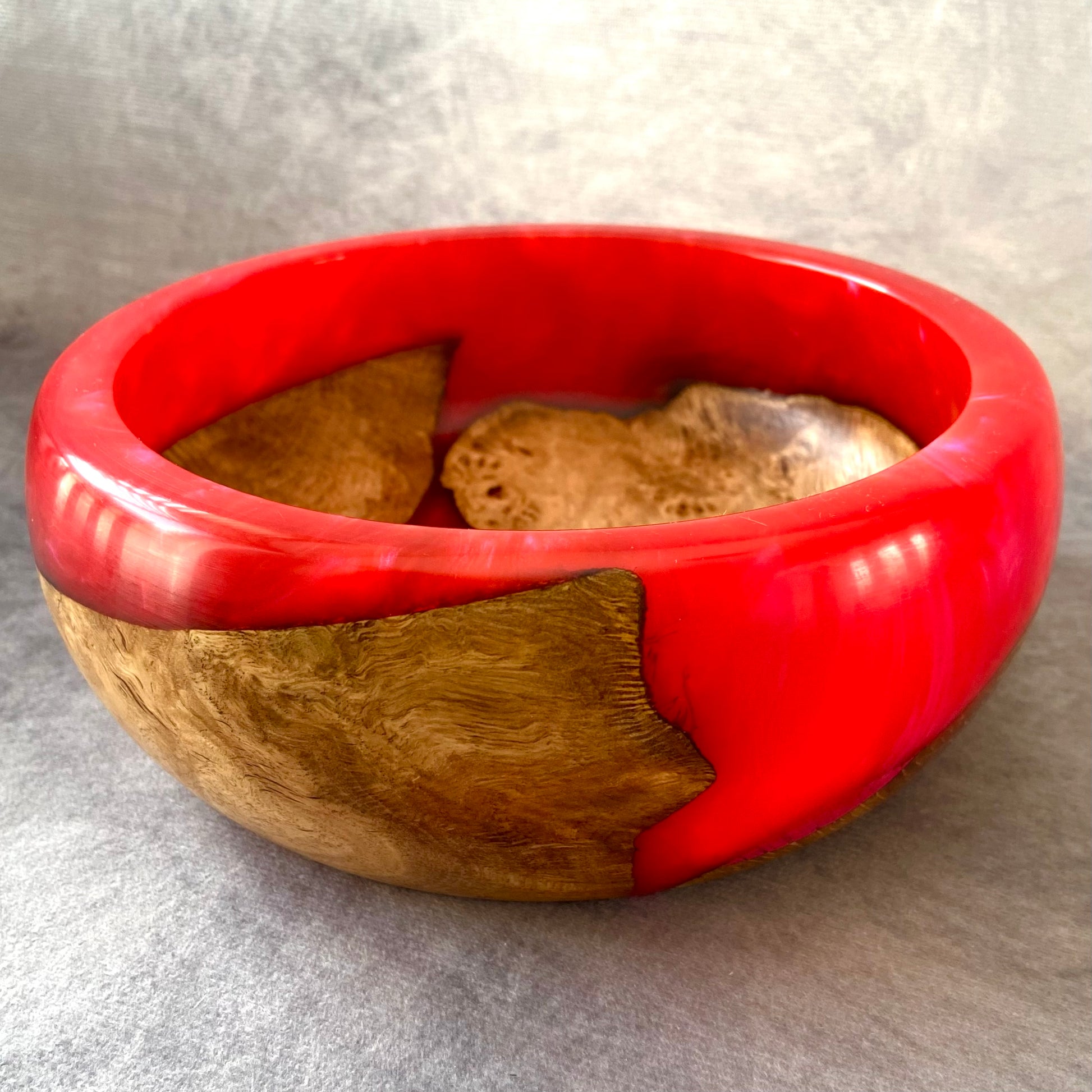 Bowl with red exterior and wooden interior on a gray background