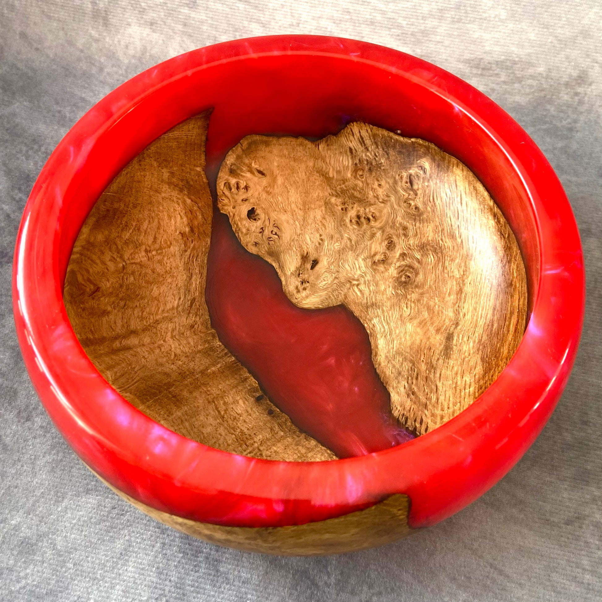 Red and gold decorative item with a face design on a gray background