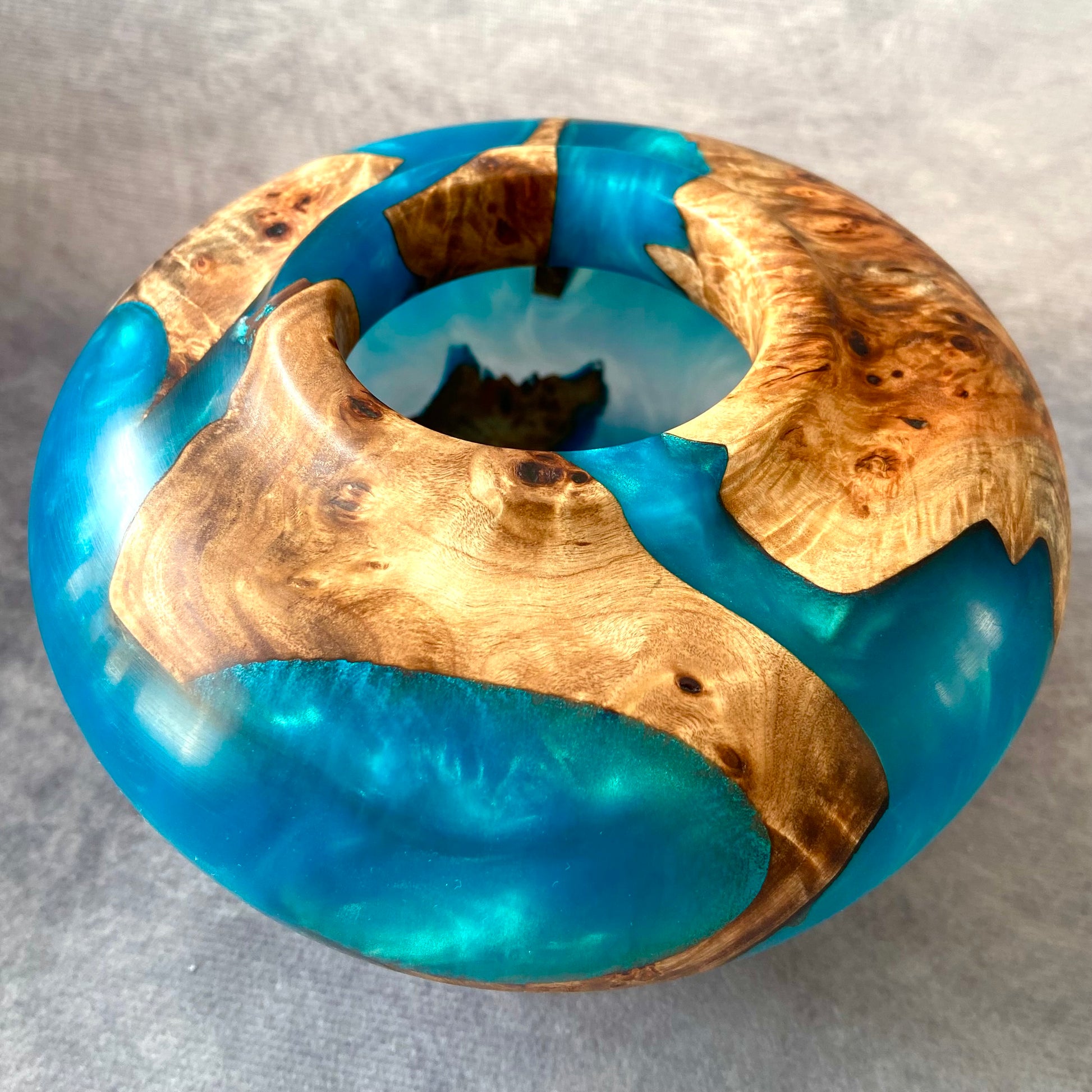 Wooden ring with blue resin inlay on a gray background