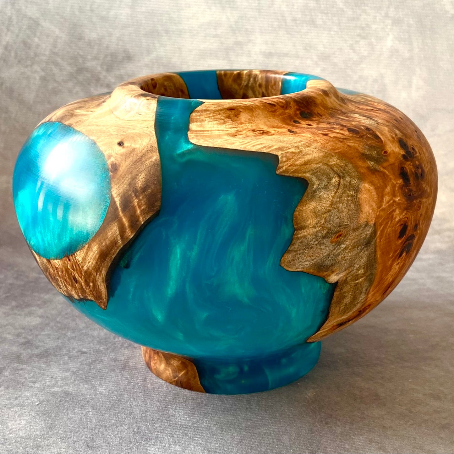 Wooden bowl with blue resin inlay on a gray background