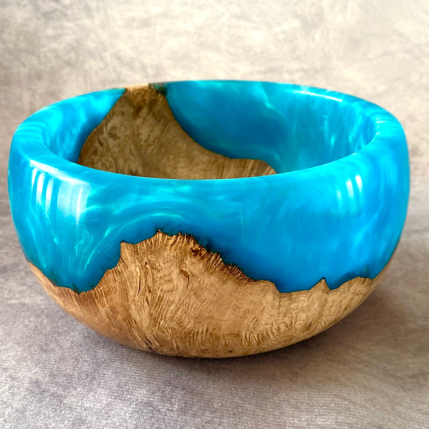 Wooden bowl with blue resin inlay on a gray background