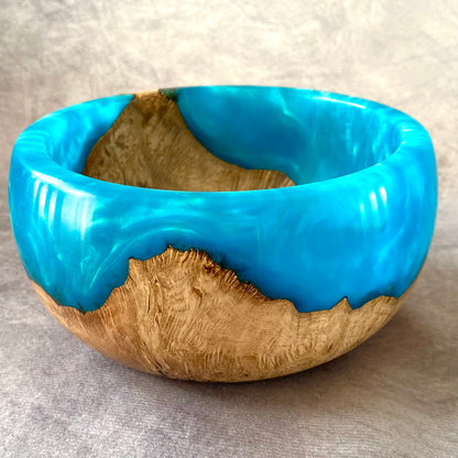 Wooden bowl with blue resin inlay on a gray background