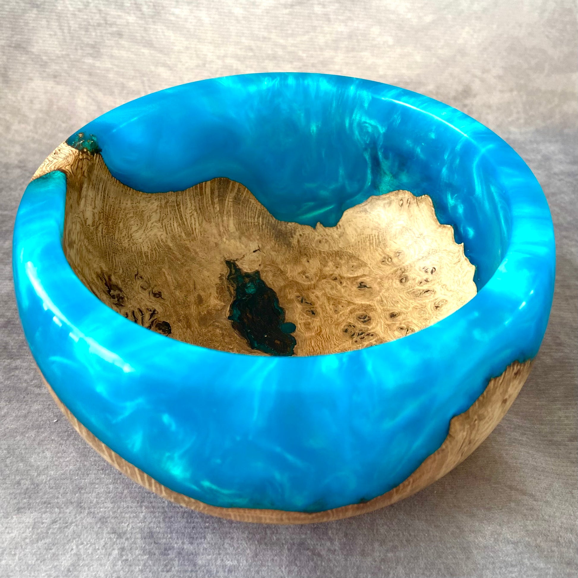 Wooden bowl with blue resin inlay on a gray background