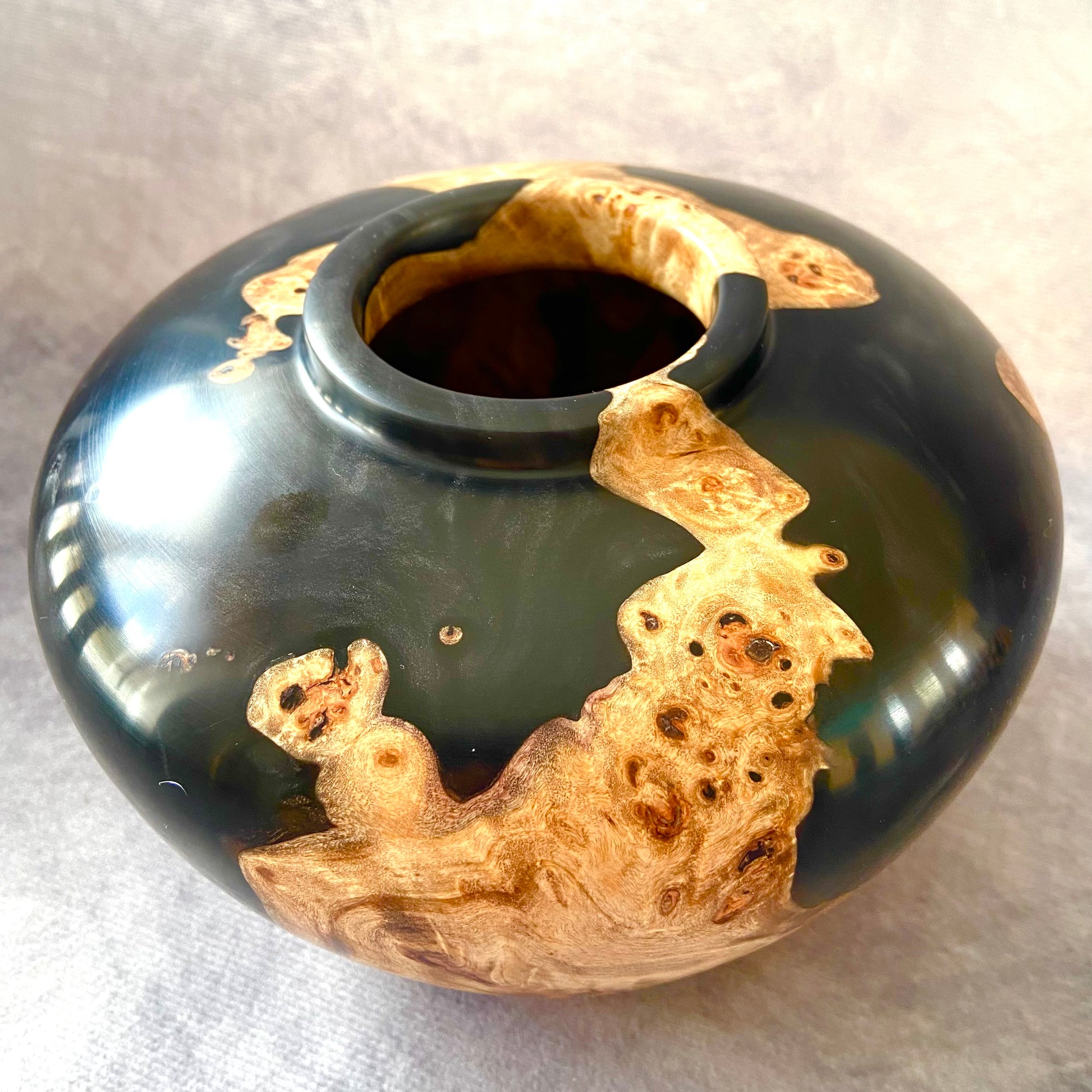 Black and gold ceramic vase on a light gray background