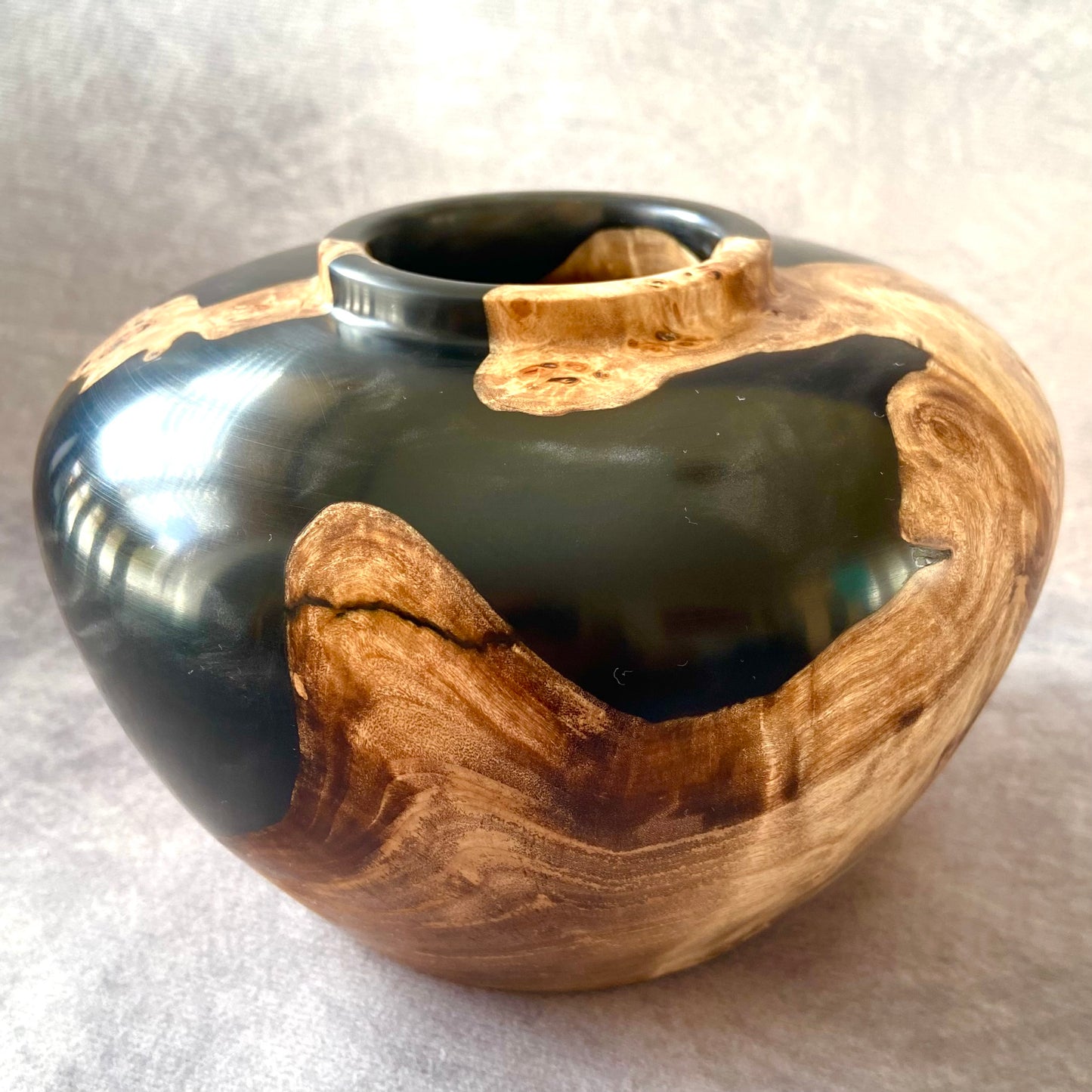 Wooden vase with black interior on a light gray background
