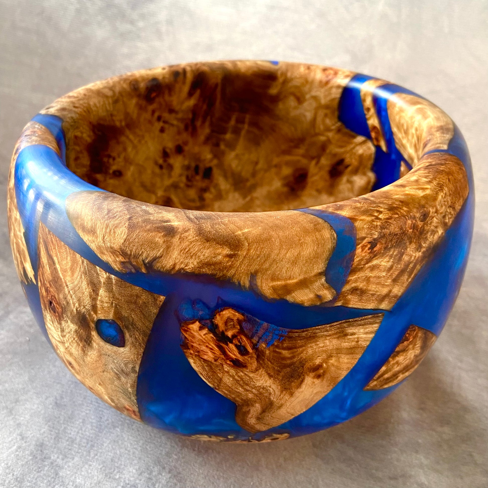 Wooden bowl with blue resin inlay on a gray background