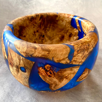 Wooden bowl with blue resin inlay on a gray background