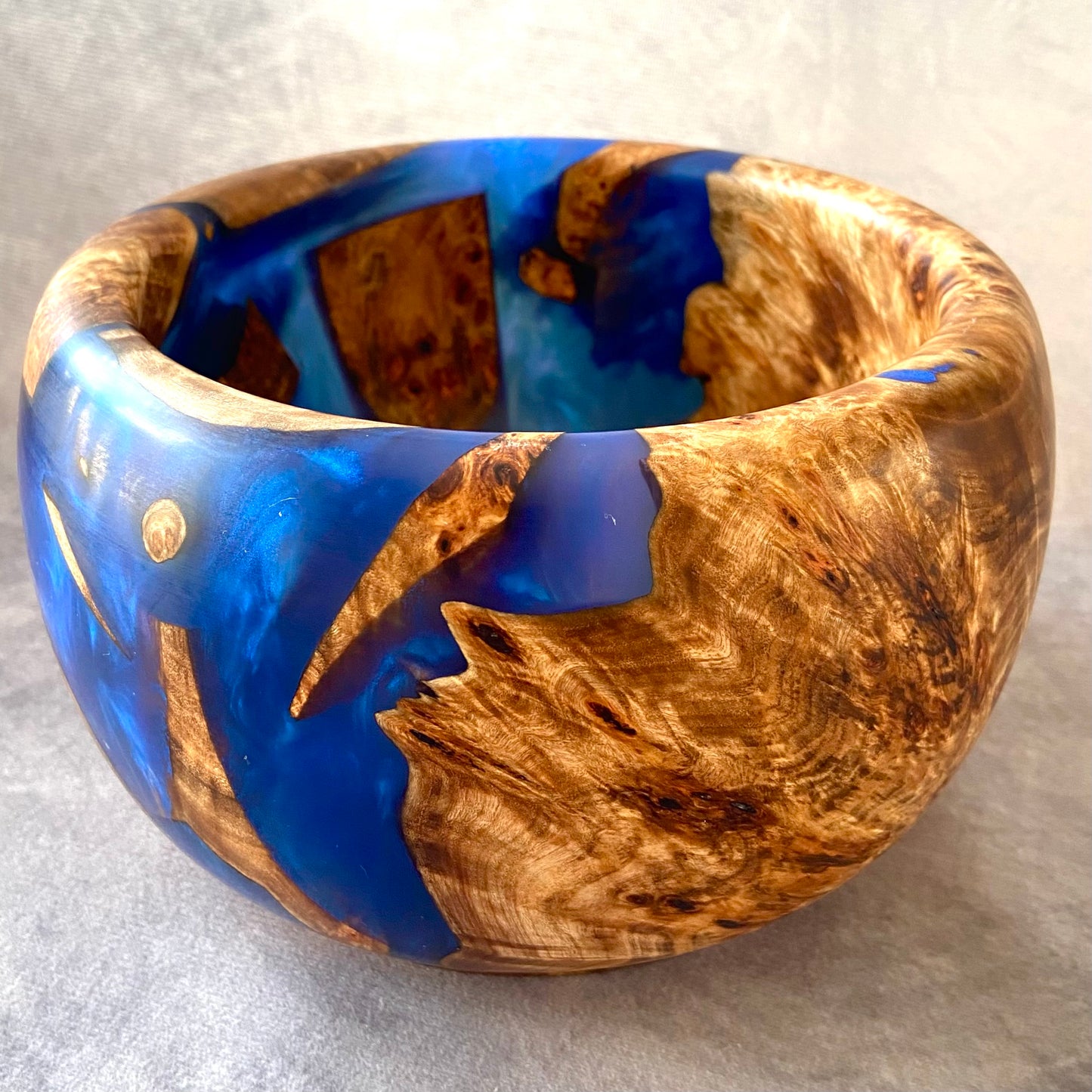 Wooden bowl with blue resin inlay on a gray background