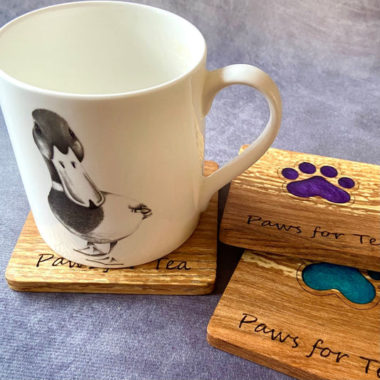 Hardwood coaster with resin paw design and laser cut text shown with mug