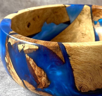 Close up detail of Mappa Burr pieces embedded in cobalt blue resin