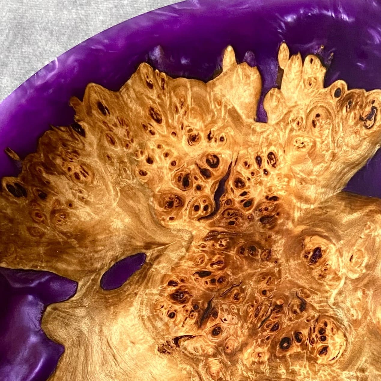 Close up texture of Mappa Burr grain meeting deep purple resin