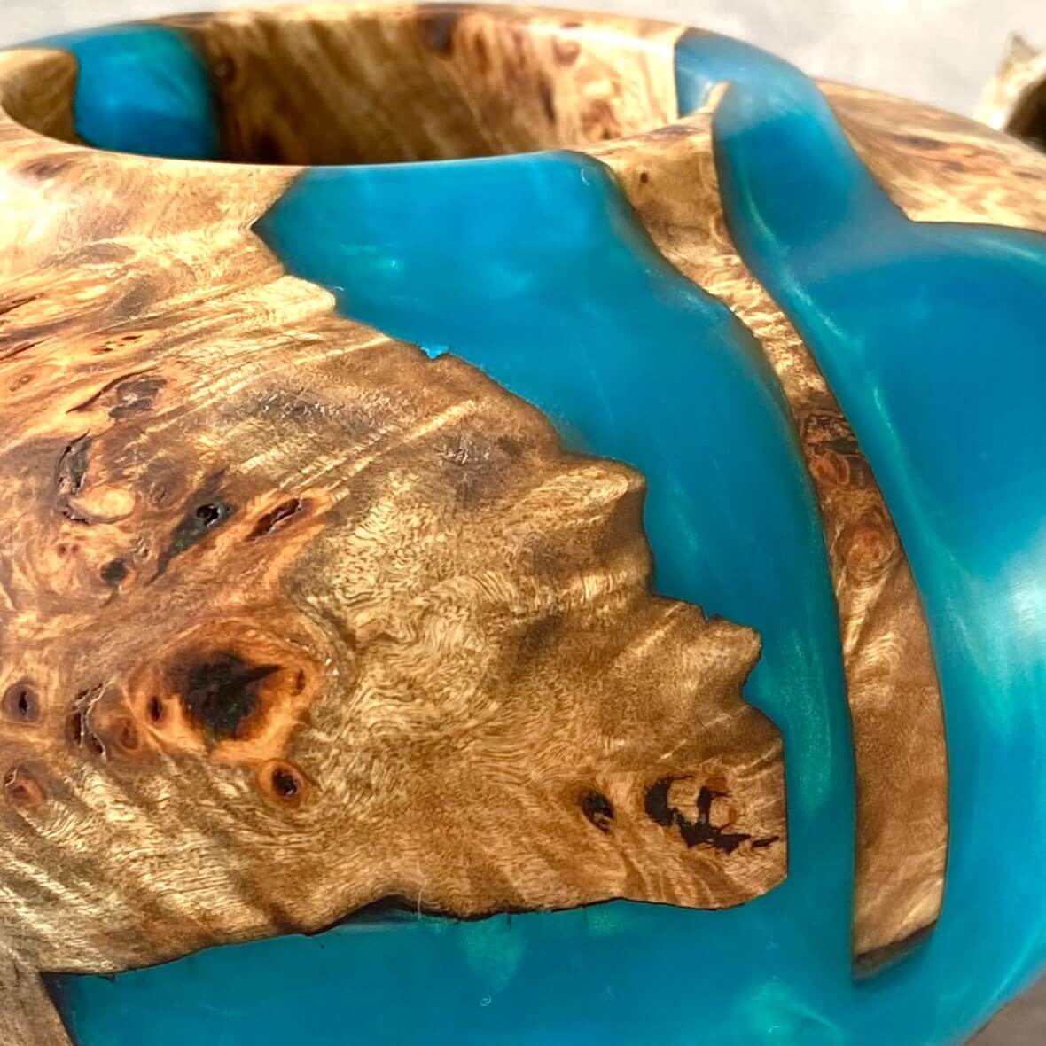 Close up texture of Mappa Burr grain meeting luminous turquoise resin