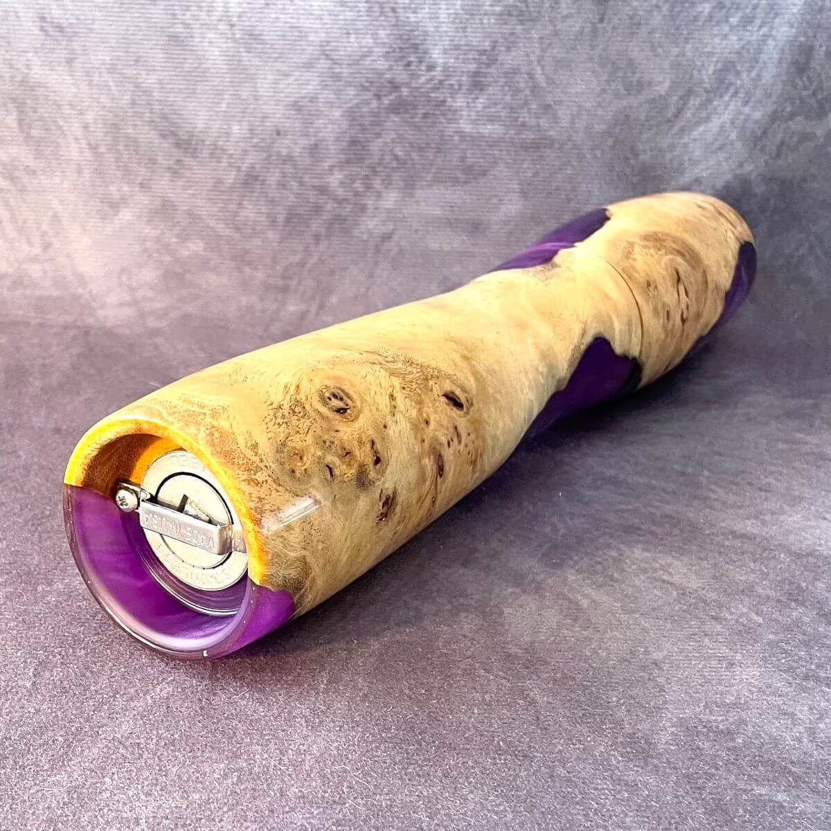 Close up bottome view of clustered grain and high-gloss finish on Mappa Burr and purple resin pepper mill showing grinding mechanism

