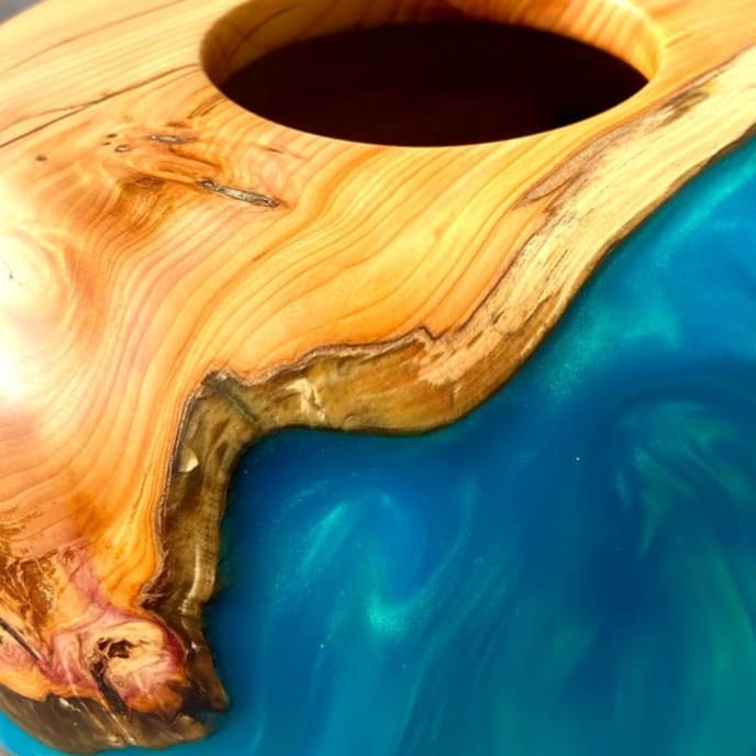 Close up texture of English Yew grain meeting luminous turquoise resin
