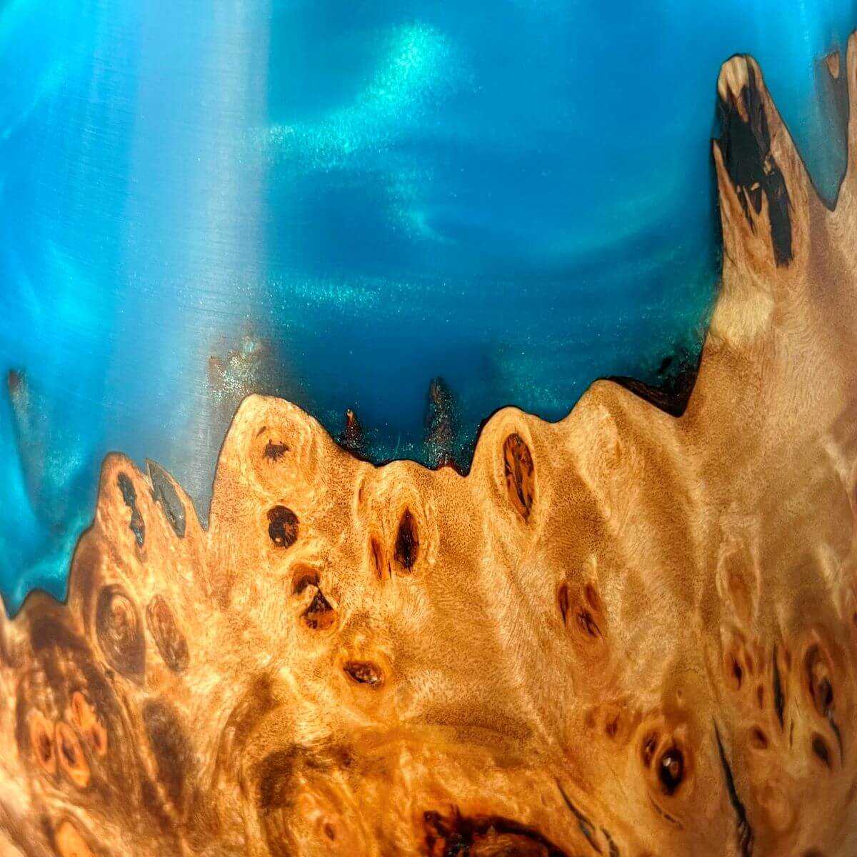 Close up of the vibrant turquoise decorative resin and Mappa burr wood grain on a handmade art vessel. Crafted in the UK.
