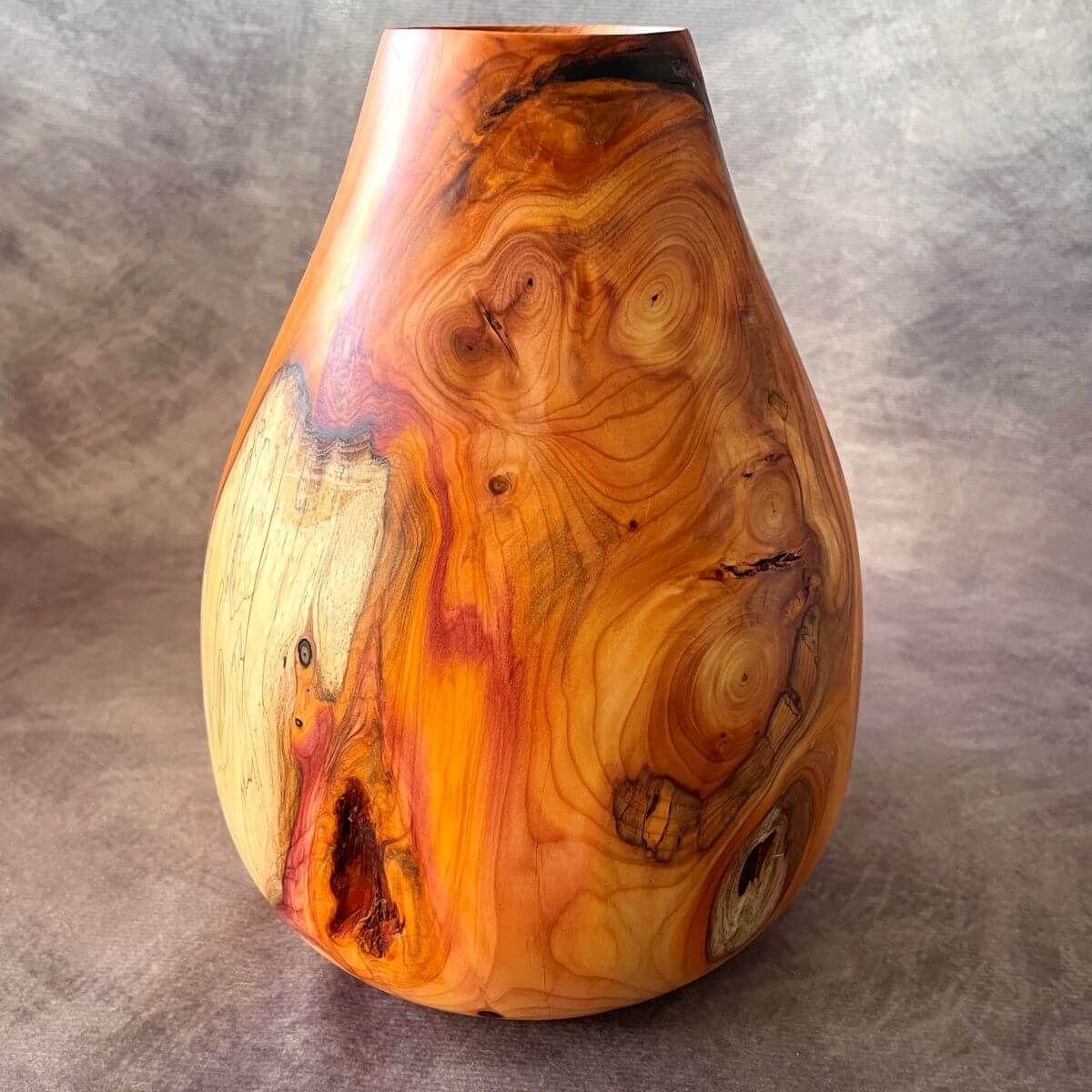A 200mm tall English yew hollow form showcasing rich orange and red grain. A unique piece of sculptured wood and turned art
