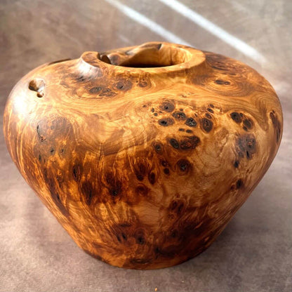 Side view of a Mappa burr turned wood vessel with natural live edges and voids.