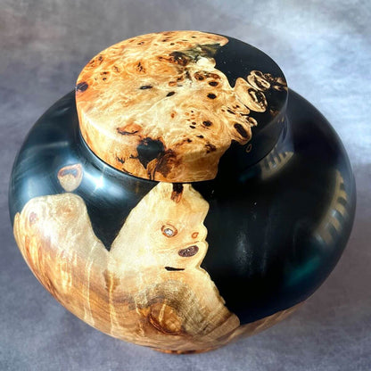 Top angle of a handmade burr wood pet urn  showing the natural burl grain and black resin.