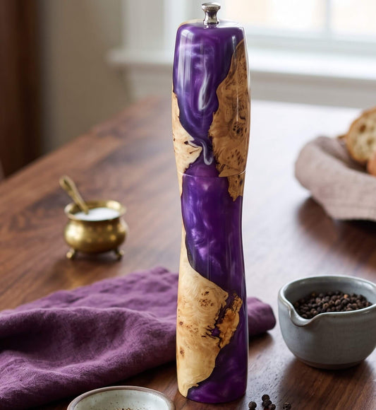 handmade purple resin and mappa burl pepper grinder shown on worktop in modern kitchen with cloth and pepper corns