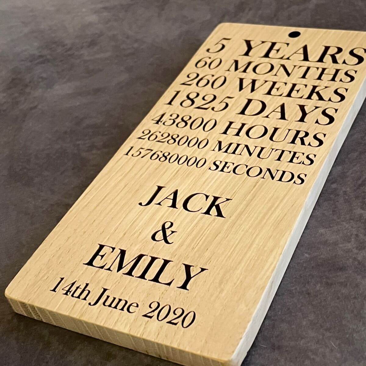 Wooden plaque with a countdown of time for a 5-year anniversary, engraved with names and date.
