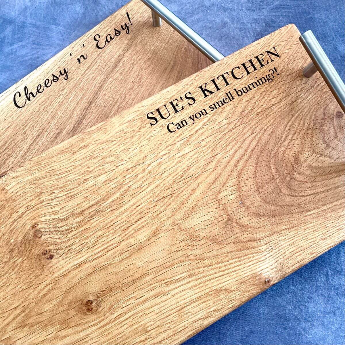 Close-up detail of the top right corner of pair of oak serving boards showing deep laser etched names and date. A traditional 5th wedding anniversary gift made from solid wood.