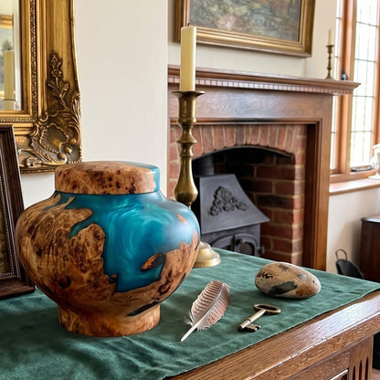 Small dog urn for ashes displayed on an oak surface with a framed photograph.
